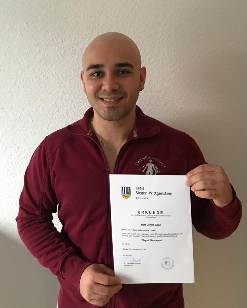 Herr Cemre Genc zeigt stolz seine Anerkennungsurkunde als Physiotherapeut in Deutschland, vermittelt durch DIH PflegeDirekt.