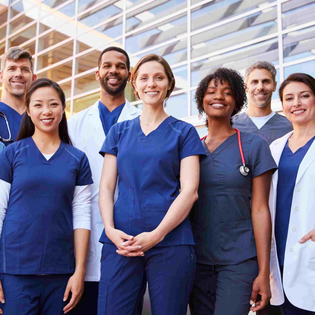 Pflegefachkräfte im Team vor einem modernen Krankenhaus, symbolisiert Vielfalt und berufliche Chancen im Gesundheitswesen.