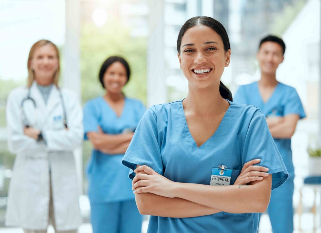 Eine lächelnde Pflegekraft in blauer Uniform, begleitet von einem multikulturellen Team aus Pflegekräften und Ärzten in einem modernen Krankenhaus.