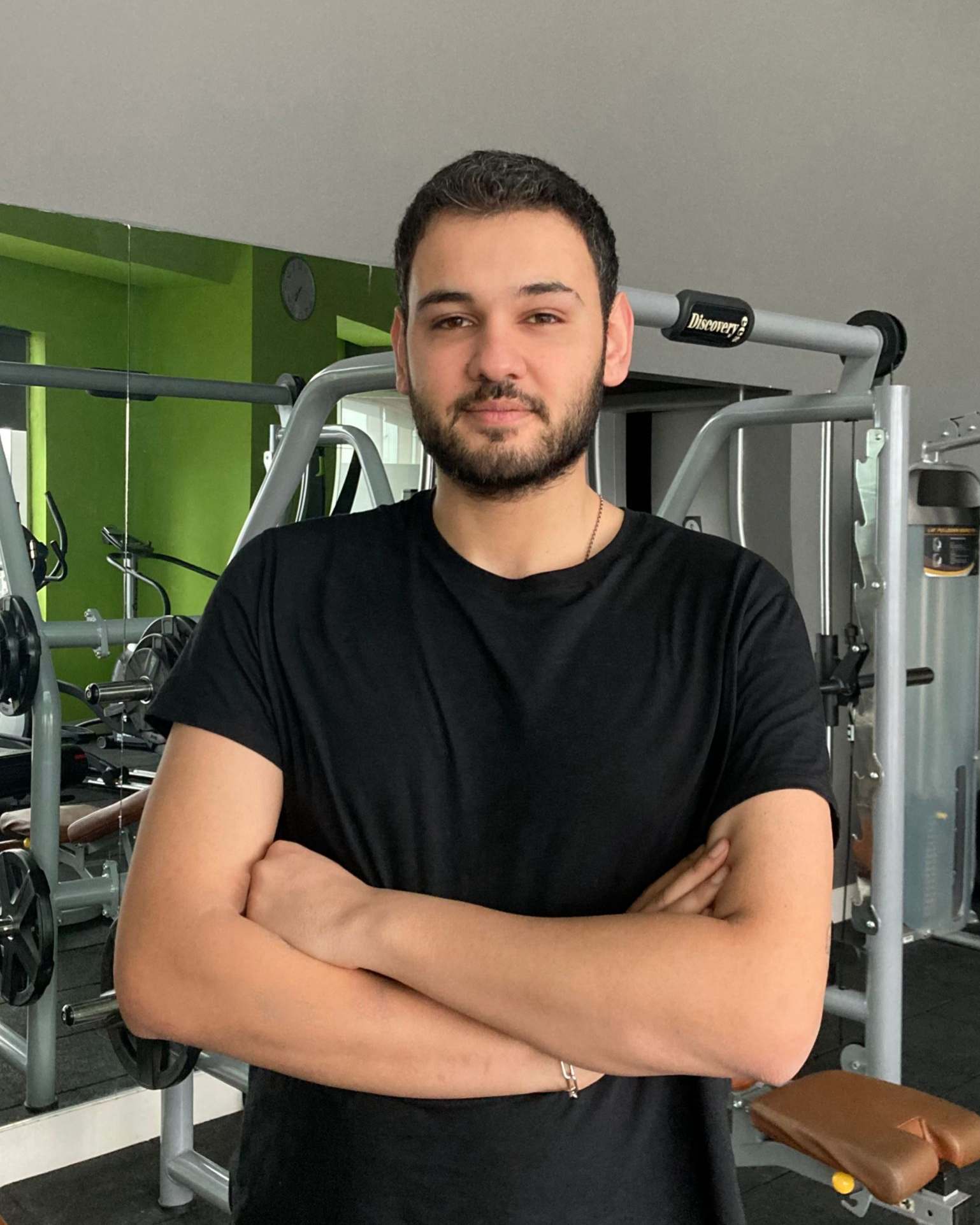 Physiotherapeut Ismail im Fitnessstudio mit verschränkten Armen – erfolgreicher Start in Bühl mit DIH ProPhysio.
