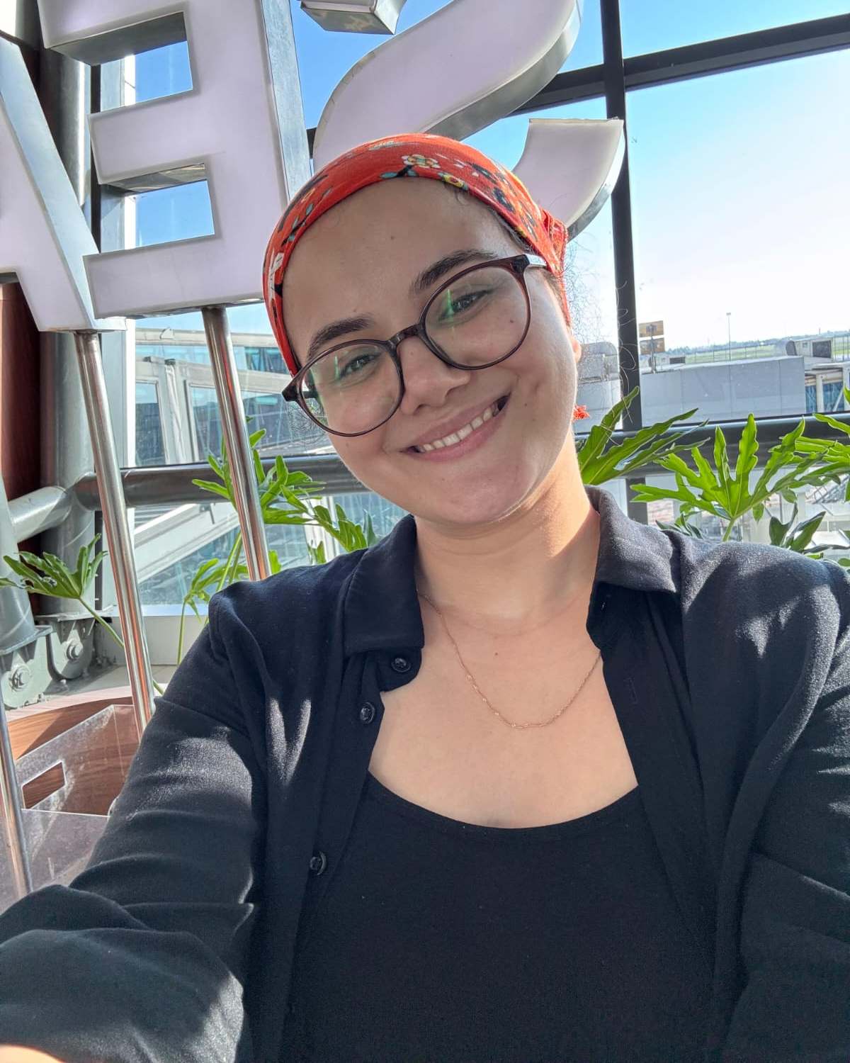 Physiotherapeutin Defne mit Kopftuch und Brille, lächelnd am sonnigen Klinikstandort in Walsrode.