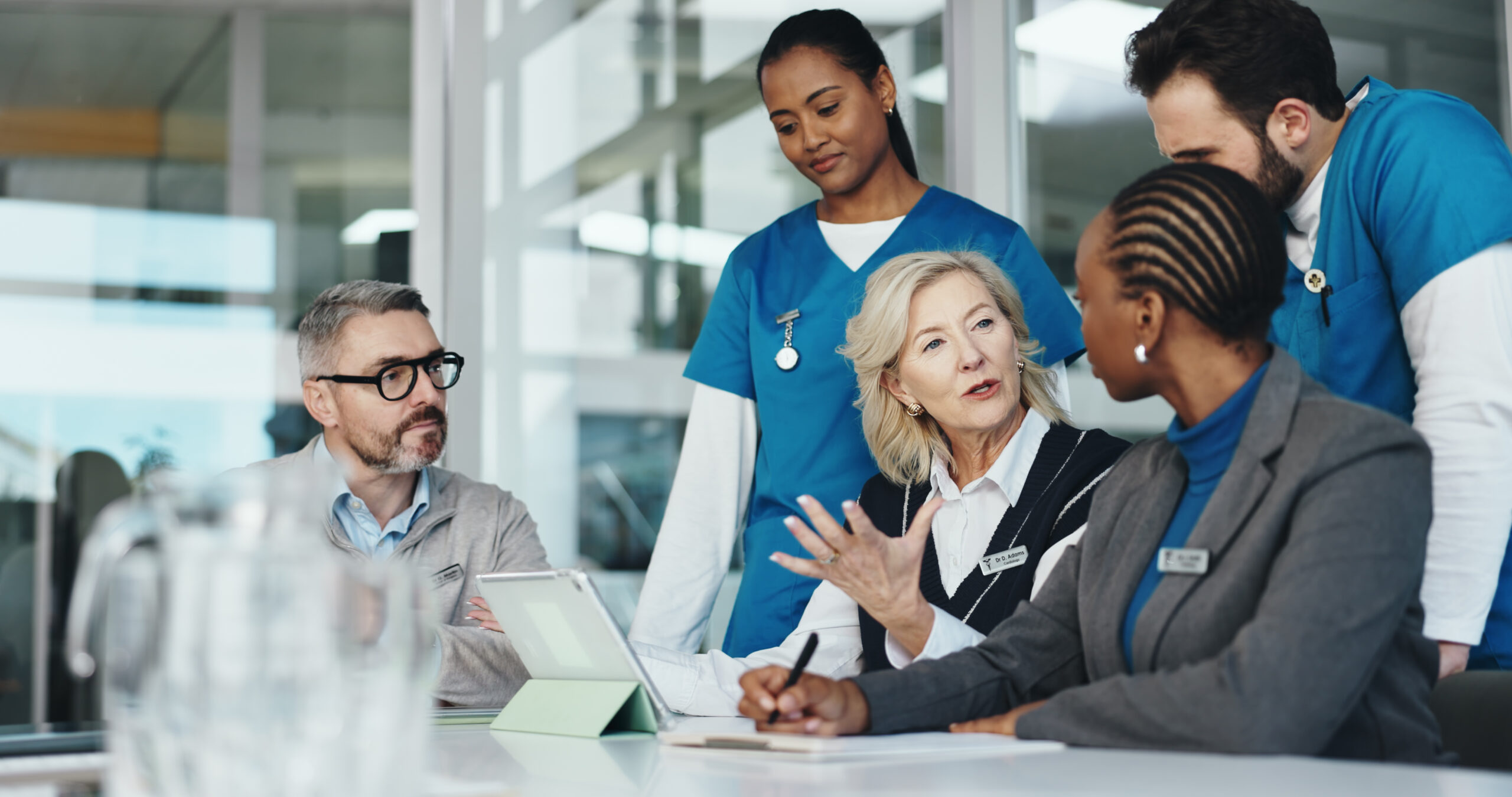 FAQ für Arbeitgeber: Gruppe von Pflegekräften im Gespräch mit Direktor und Personalchef