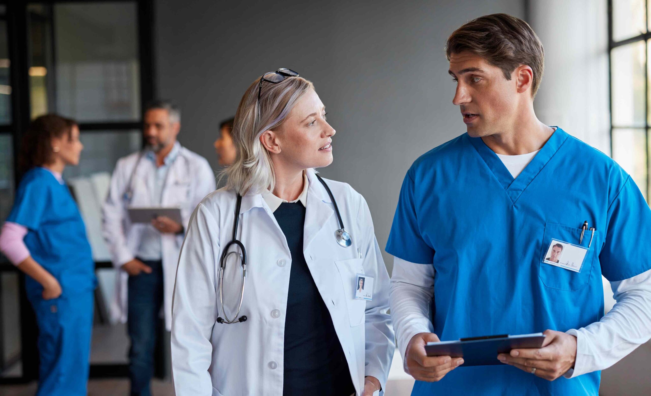 Ärztin und Pflegefachkraft besprechen gemeinsam den Pflegeplan im Klinikflur